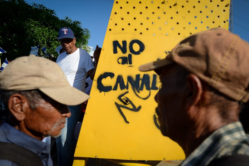 Un grupo de campesinos frente a una pinta anti Canal hecha en uno de los llamados "Árboles de la Vida", símbolo del poder del Gobierno del presidente Ortega. Carlos Herrera | Confidencial.