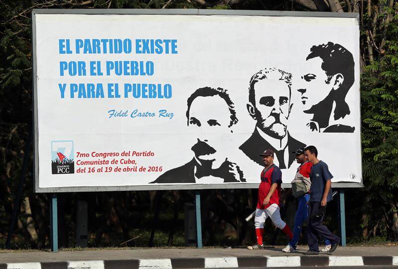 Tres hombres caminan junto a un cartel alusivo al VII Congreso del Partido Comunista de Cuba, hoy sábado 16 de abril, en La Habana (Cuba).  EFE/Alejandro Ernesto