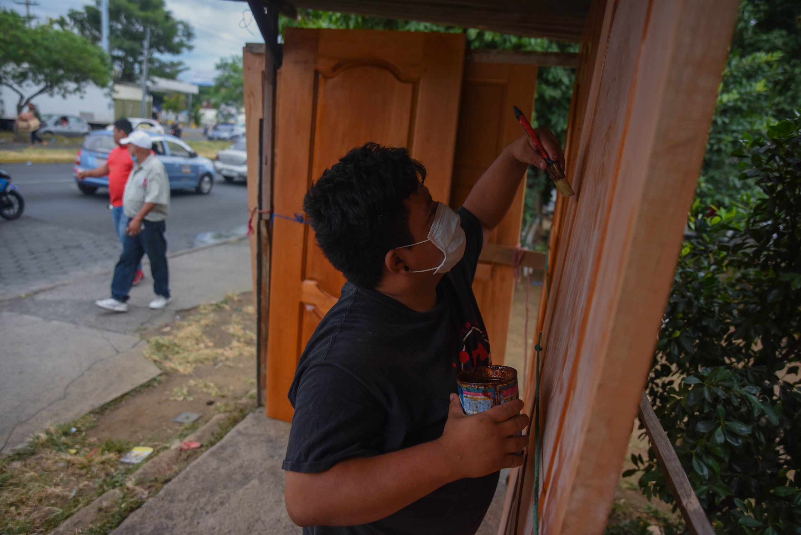 Enmanuel Mendoza, de 22 años, barniza una de las puertas que vende en un anden cerca de los semáforos d e la Centroamérica// Foto: Nayira Valenzuela | Confidencial