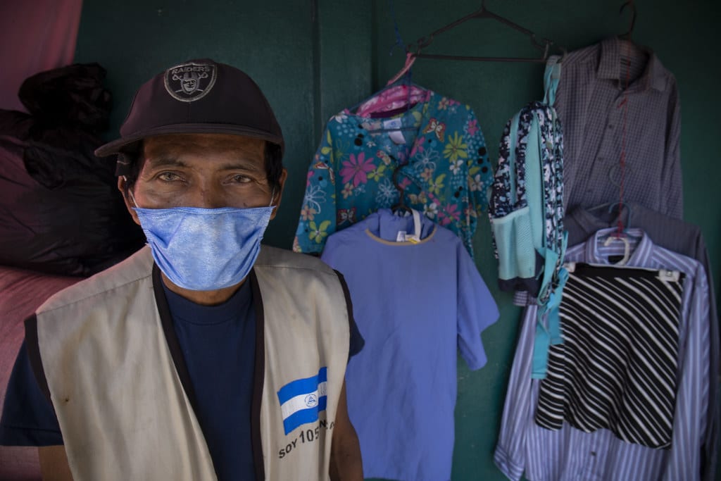 Mateo Mendoza, un jubilado de 76 años, anexó un perchero lleno de gabachas medicas a su venta de jocotes y mangos, ubicada en la entrada del Hospital Roberto Huembes. // Foto: Nayira Valenzuela | Confidencial
