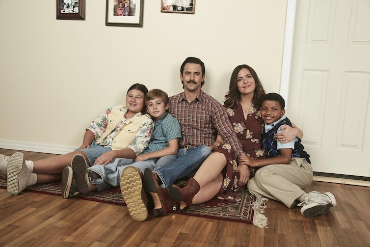 Dos padres jóvenes posan para la foto con sus hijos, tres niños de unos 12 años.